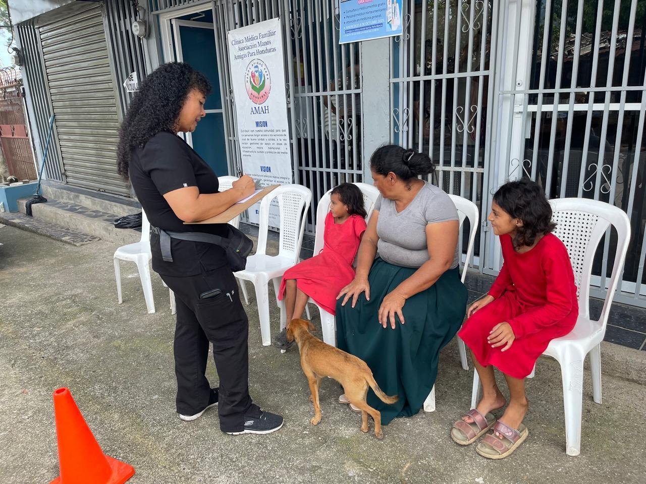 A family waits outside the clinic while a health worker takes their information.