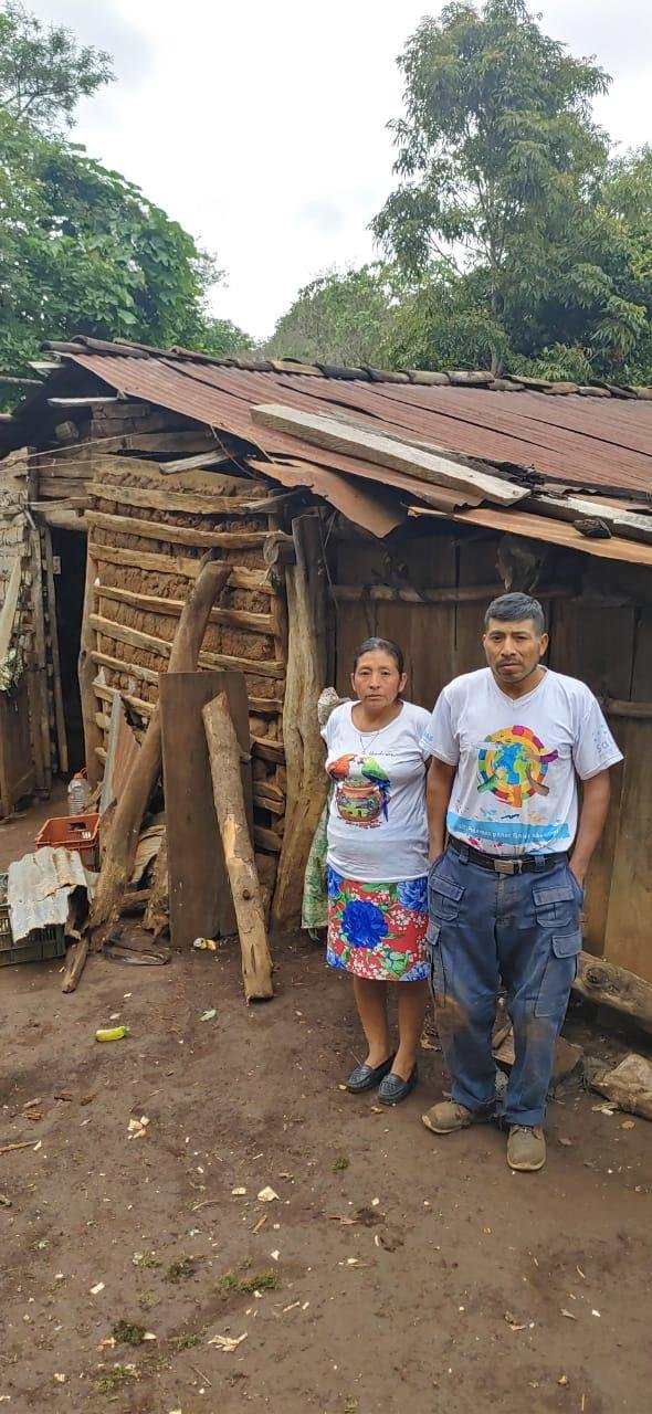 A family at a bahareque home with a ruined tin roof, without electric service.