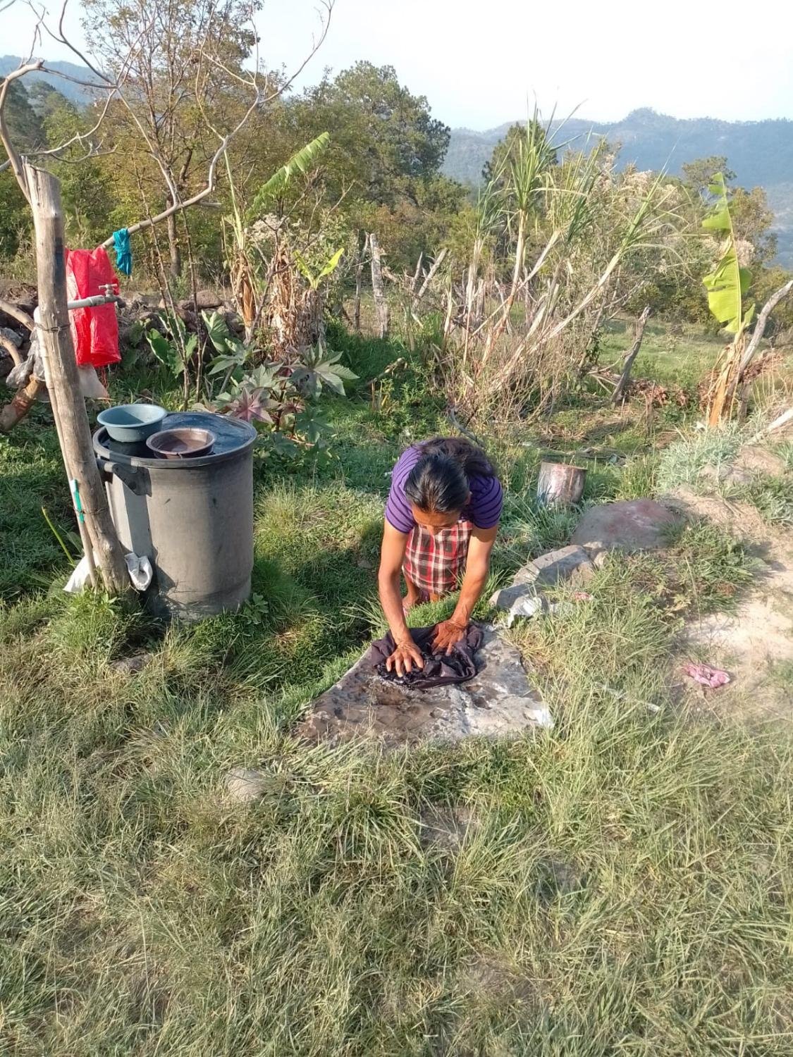 Washing clothes on a stone. Many homes still have no wash-place and no safe water close by.