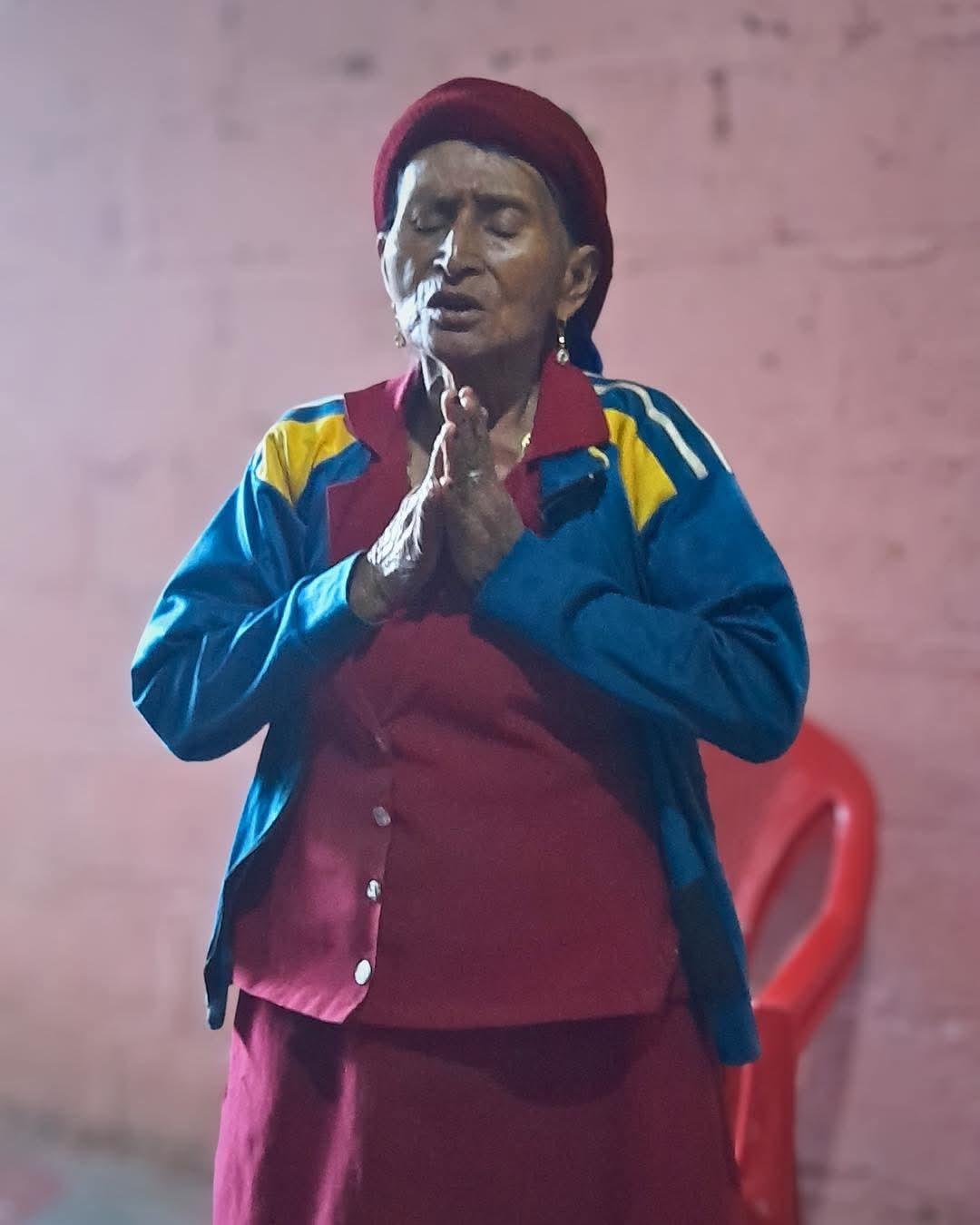 A sister of the church in Honduras praying with her eyes closed and her hands together.