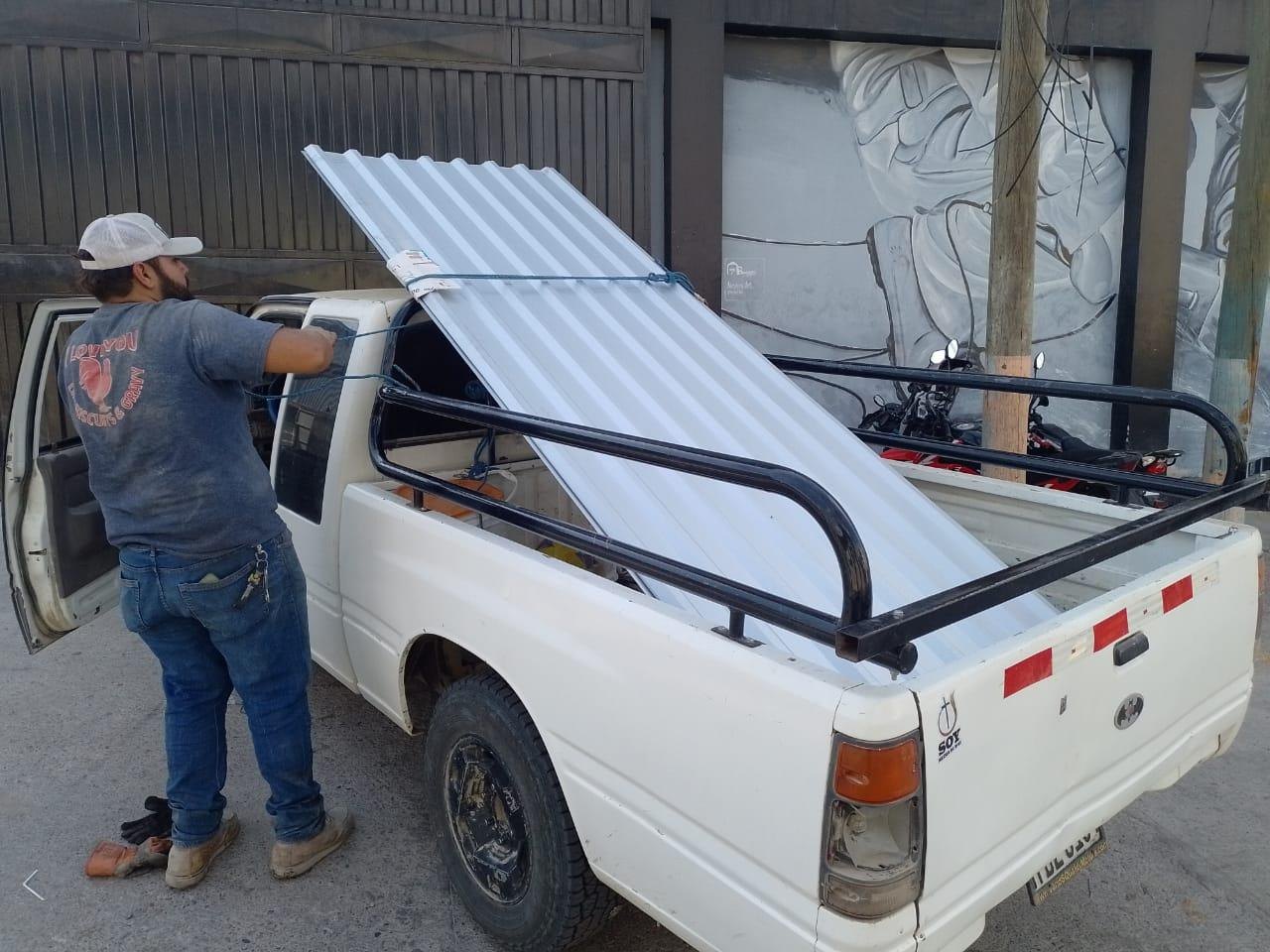 Corrugated roofing sheets being tied onto a truck for families in Honduras.